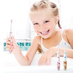 Bright young girl smiling with a colorful cartoon toothbrush in bathroom setting for kids dental hygiene.