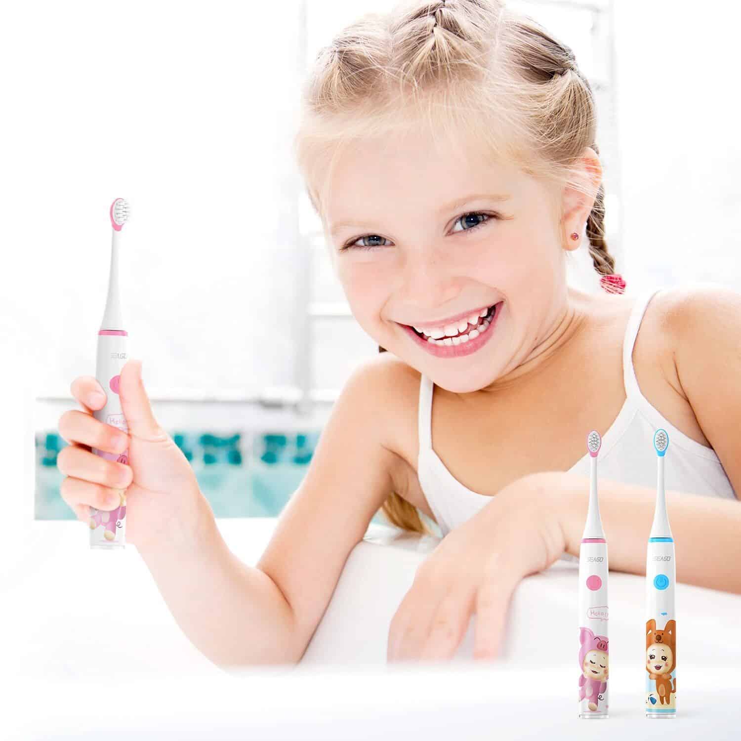 Bright young girl smiling with a colorful cartoon toothbrush in bathroom setting for kids dental hygiene.