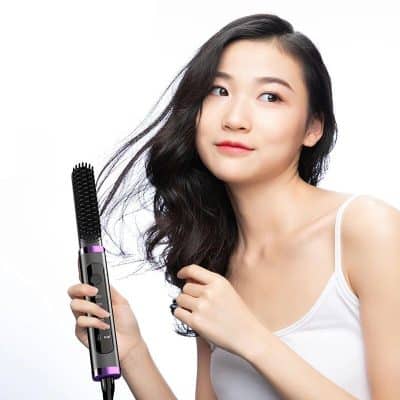 Young woman using a heated styling brush for smooth, shiny hair, showcasing hair care and styling tools from Monalisa Medical.