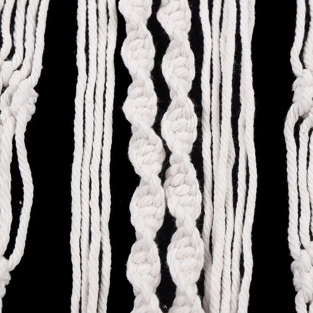 Colorful bohemian yarn wall hanging with white, black, and neutral tones, perfect for enhancing modern or rustic interior spaces. Unique textile art piece for stylish home or office decor.
