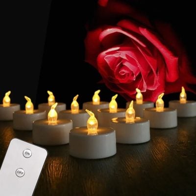Romantic tea light candles creating a cozy ambiance, perfect for romantic settings or relaxing moments, with a stunning red rose in the background for a touch of elegance and love.