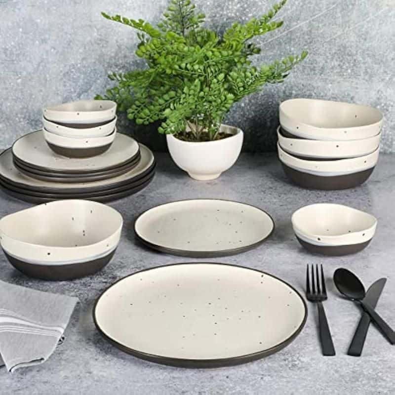Elegant ceramic dinnerware with black accents, perfect for modern dining. Includes bowls, plates, and utensils, ideal for everyday meals or special occasions.