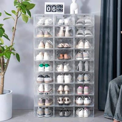 Clear shoe storage box filled with various sneakers and casual shoes arranged neatly. Perfect for organizing footwear in bedroom or closet space. Modern design complements interior decor.