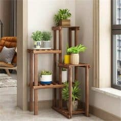 A stylish wooden plant stand with multiple tiers showcasing vibrant indoor plants, perfect for a contemporary home office or living room.