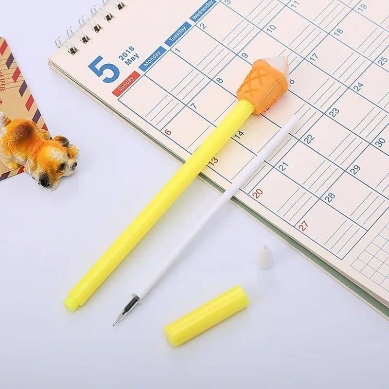 Close-up of a desk calendar for May 2018 with a playful ice cream pen, a white pen, and a small dog toy, perfect for organizing appointments and vision care schedules.
