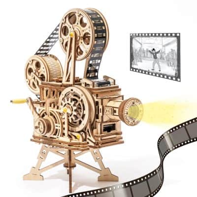 A wooden mechanical film projector with gears, reels, and a beam of light projecting film strips, used for movie projection and film viewing.