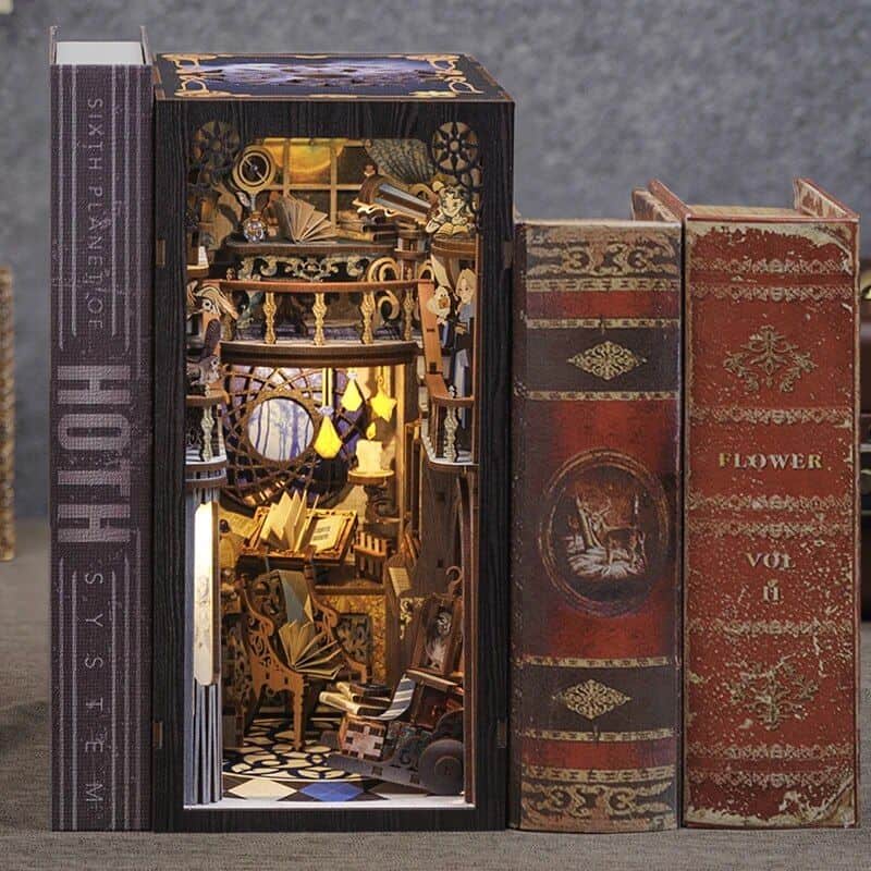 A miniature library scene inside a decorative box with tiny books, lamps, and furniture, surrounded by vintage book covers. Perfect for home decor, collectibles, and unique gift ideas.