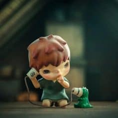 Adorable kid figurine holding a vintage phone with a small green dinosaur, perfect for collectible displays and adding charm to your home or office decor.