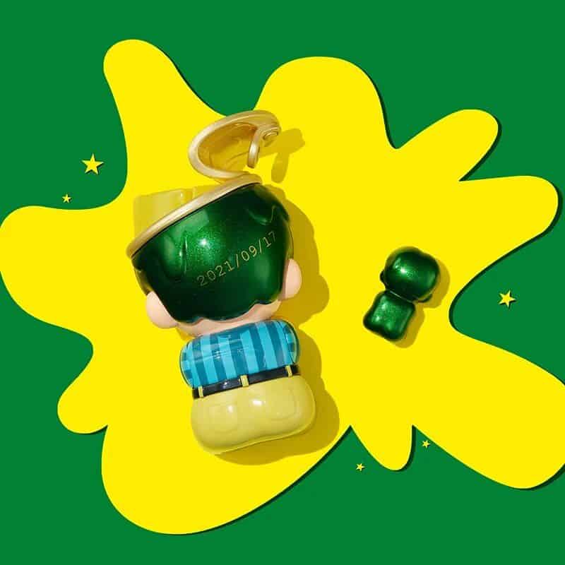 Colorful novelty keychain with a shiny green apple design, featuring a character and an attached small apple charm. Perfect for accessories and gifts.