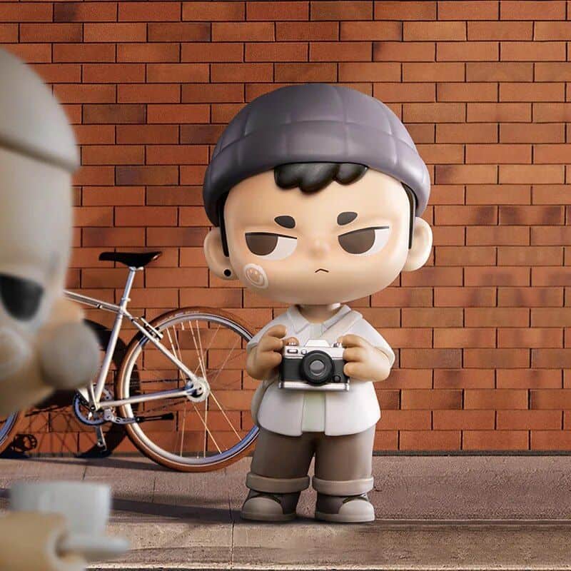 Charming cartoon boy holding a camera, standing beside a stylish bicycle against a brick wall, perfect for optometry store imagery emphasizing photography, vision, and eyewear lifestyle.