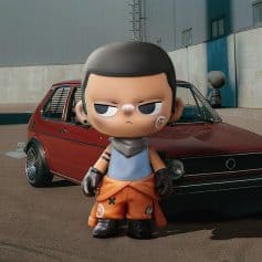 Cute stylized toy figure of a street racer with a rebellious look, standing in front of a red vintage car outside an industrial building.