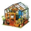 A miniature glasshouse with vibrant plants and decorative accents, ideal for indoor gardening enthusiasts seeking a stylish green space. The greenhouse features a charming design perfect for home or office.