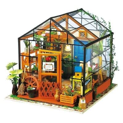 A miniature glasshouse with vibrant plants and decorative accents, ideal for indoor gardening enthusiasts seeking a stylish green space. The greenhouse features a charming design perfect for home or office.