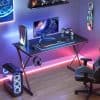 A high-tech gaming workspace with neon lighting, LED display, gaming chair, VR headset, and stylish decor, perfect for eSports and gaming enthusiasts.