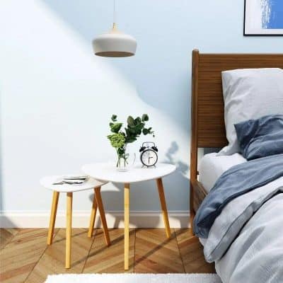 Bright interior bedroom with stylish wooden bed, fresh bedding, and minimalist side tables with plants and alarm clock. Perfect for cozy, relaxing sleep environment.