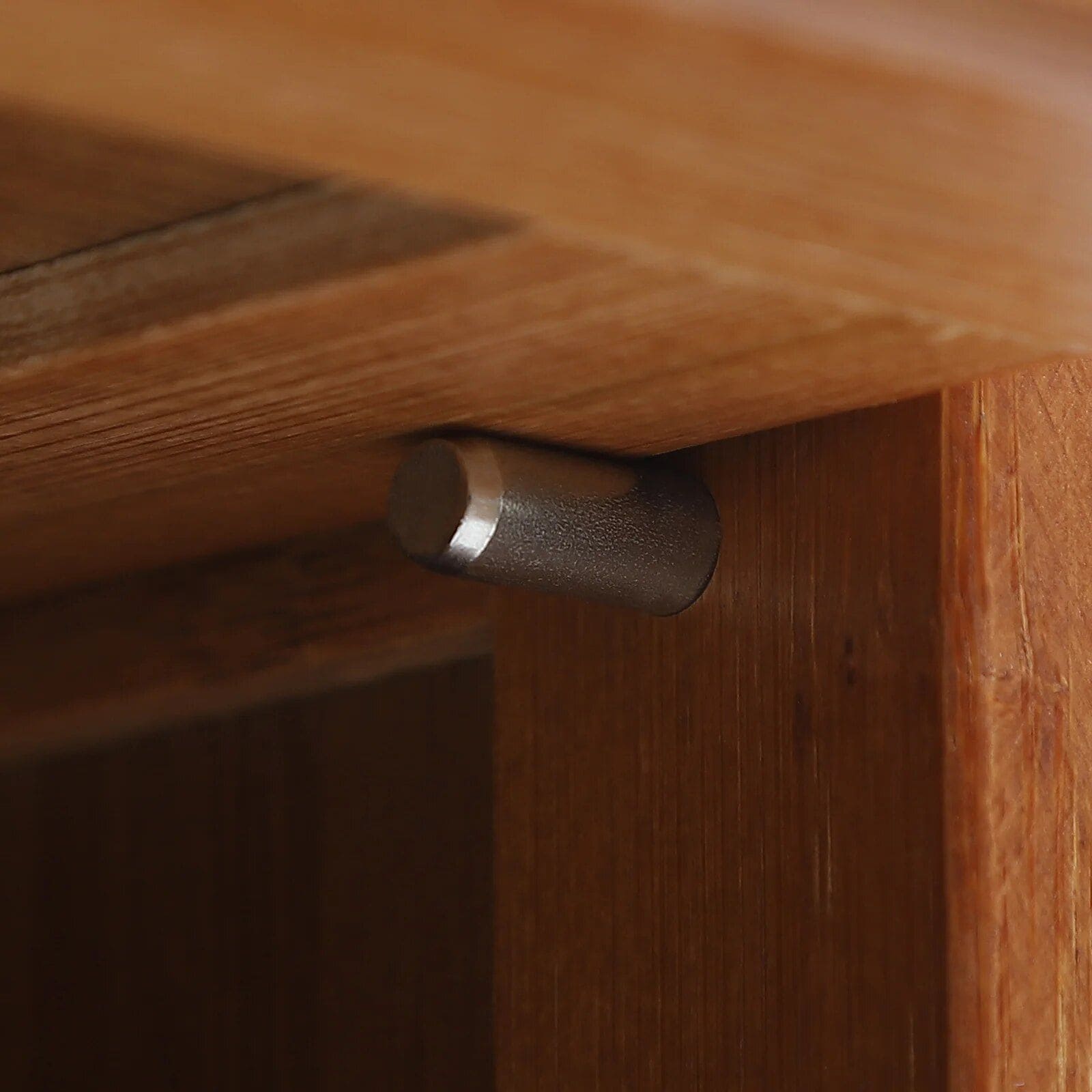Close-up of a metal hinge connecting wood panels, showcasing high-quality craftsmanship in elegant furniture design. Ideal for enhancing the stability and aesthetic appeal of home or office furniture.