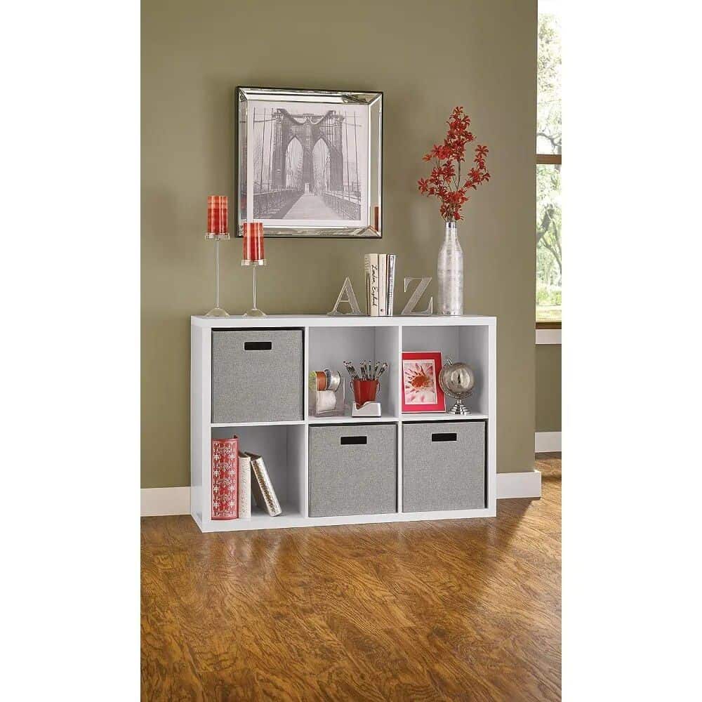 Versatile storage cube with gray fabric drawers and decorative accessories, ideal for organizing household items, perfect for living rooms or bedrooms.