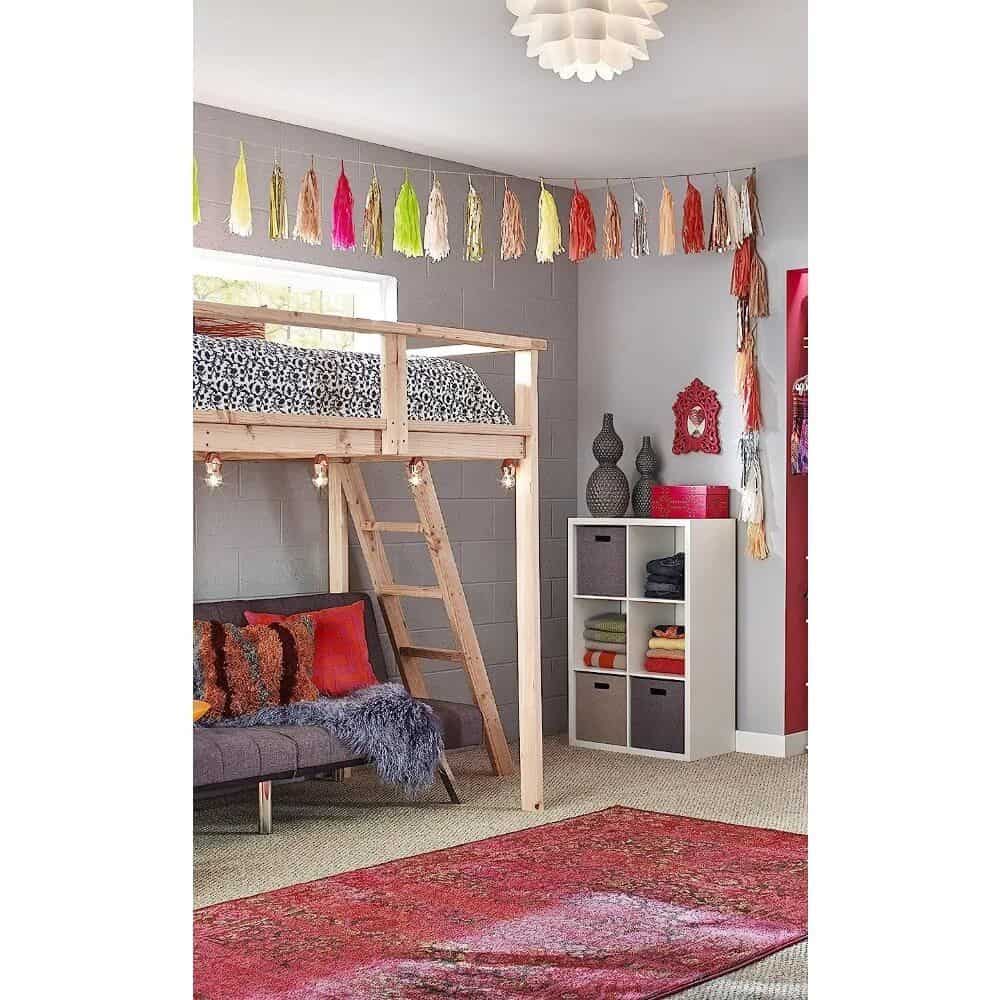 Vibrant tassel garland hanging in a cozy kids' bedroom with a loft bed, decorative cushions, and storage cubes, perfect for playful nursery or kids’ room decor.