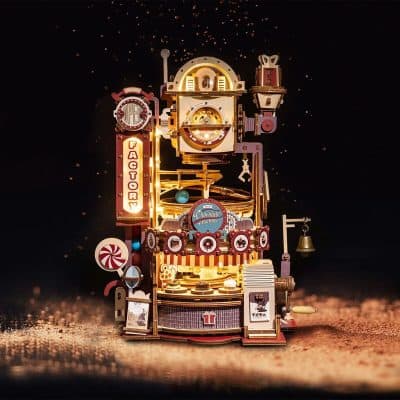 Brightly lit miniature toy factory illuminated against a dark background, featuring festive candy canes, a bell, and whimsical decorations perfect for holiday decor and toy-themed celebrations.