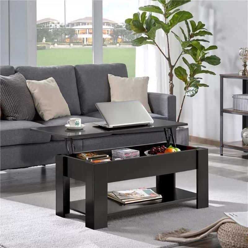 Comfortable grey sofa with beige and gray pillows, fitted with a laptop. Includes a stylish black coffee table and large indoor plant, perfect for contemporary living room decor.