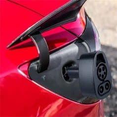 ALT: Close-up of Tesla EV charging port with charging cable inserted on a red electric car, showcasing fast-charging technology and modern design for eco-friendly transportation.