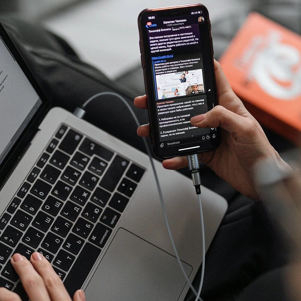 Close-up of a person browsing a smartphone for optical store deals. The person is using a laptop, highlighting online shopping for glasses and eyewear.
