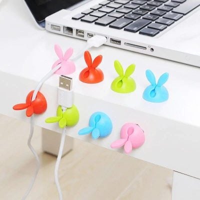 Brightly colored bunny-shaped cable protectors for USB and charging cords, preventing damage and adding fun to your tech accessories. Perfect for desk organization and cable safety.