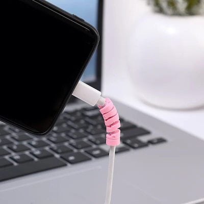 Stylish pink spiral cable organizer connecting phone to laptop charger for desk setup.