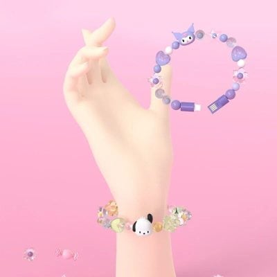 Colorful bead bracelet with playful cartoon charms on a pale hand against pink background.