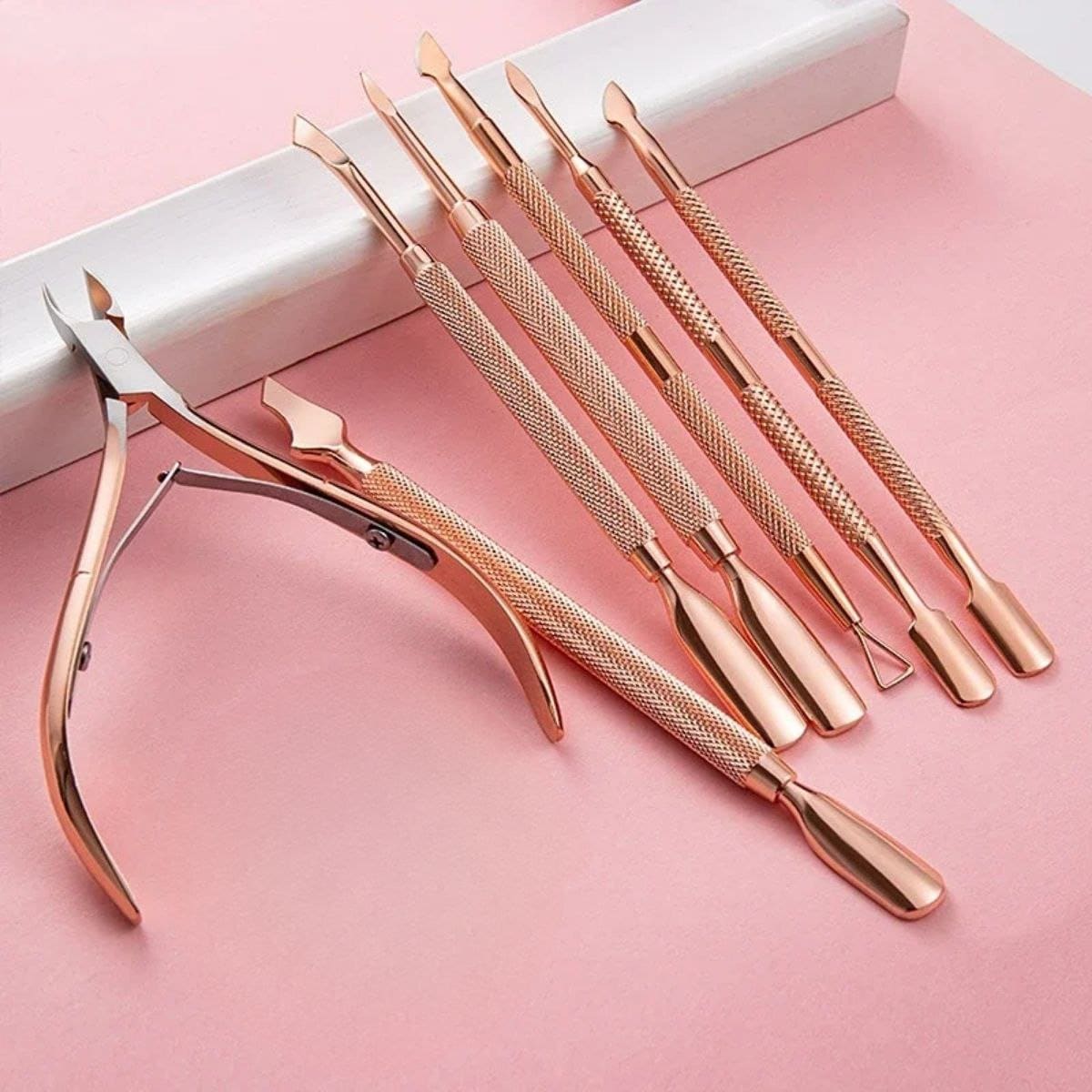 Elegant pink and rose gold manicure and pedicure tools with textured handles for precision and comfort. Perfect for professional and at-home skincare and nail care routines.