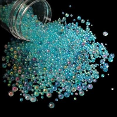 Vibrant blue, pink, and iridescent pearl beads spilled from a container, ideal for eye sparkle enhancements, jewelry, and optical accessories. Perfect for eye-catching optical fashion or decorative purposes.