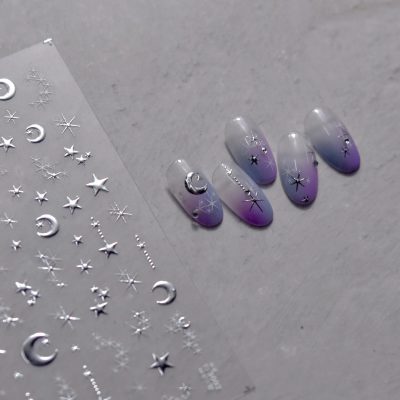 Elegant moon and star design nails with celestial motifs on a gradient purple and gray background. Perfect for stylish, themed nail art enthusiasts seeking unique nail decor.