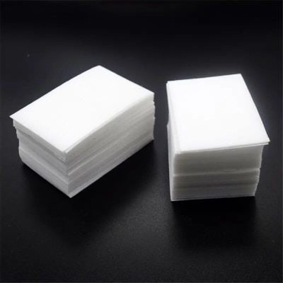 Stacked pieces of white optometry lens cleaning cloths on black background for optical store needs.