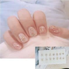 Delicate nail design featuring celestial-themed gold foil accents and star-shaped embellishments for a trendy, elegant look. Perfect for special occasions or everyday style.