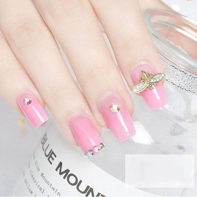 Elegant pink nail design with rhinestones and 3D bee embellishment, perfect for enhancing your look with trendy nail art accessories.
