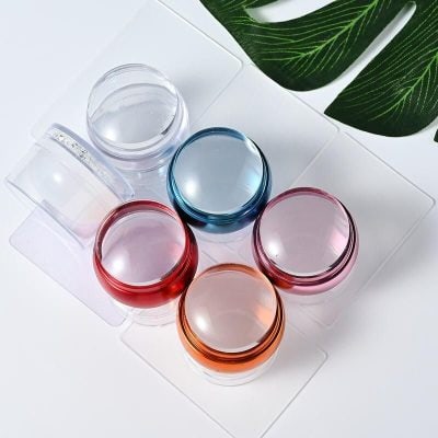 Brightly colored eye cream containers with transparent glass lids, perfect for skincare products. Ideal for cosmetic storage and beauty routines.