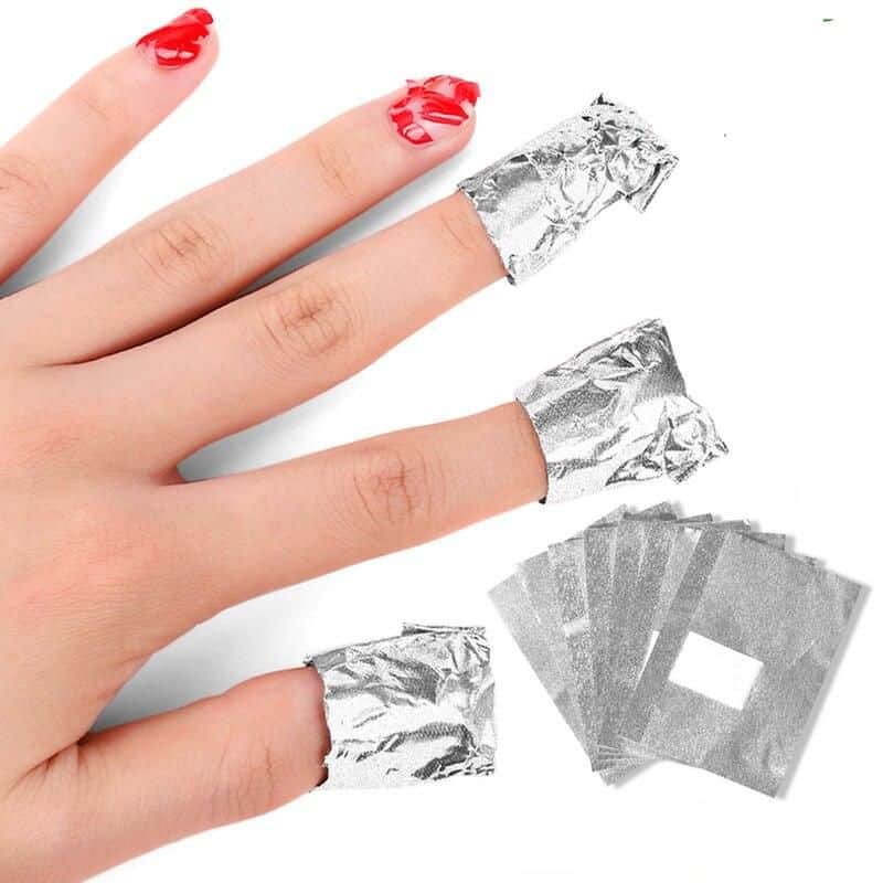 Close-up of a hand with aluminum nail wraps on fingers, demonstrating nail art and at-home manicure supplies, perfect for nail enhancement or restoration.