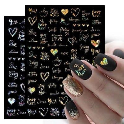 Elegant black nail design with holographic 'Just Love' and heart decals, accented by a glittery gold and clear nail. Perfect for expressing love and stylish fashion.