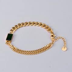 Close-up of luxurious gold chain bracelet featuring a striking green gemstone on a plain background. Perfect for fashionable accessories and jewelry shopping at Monalisa Store.
