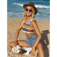 Stylish women’s summer beach outfit with colorful crochet top and denim shorts, accessorized with sunglasses, hat, and beach bag on sandy shore background. Perfect for summer style.