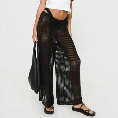 Stylish black crocheted beach pants with drawstring waist, side slits, and see-through pattern perfect for beachwear and summer fashion.