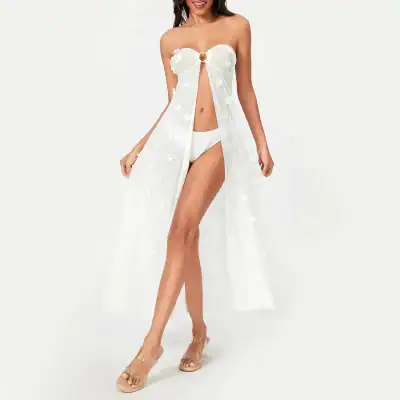 Bright white summer dress with floral appliqué, sleeveless, and flowy design. Perfect for beach or casual outings, offering a stylish and comfortable look.