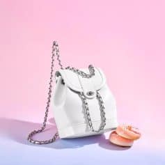 Elegant white handbag with silver chain strap on soft pastel background. Perfect accessory for fashion-forward styles, blending luxury and modern elegance.