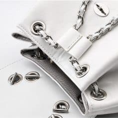 Elegant white handbag with silver chain strap and grommet details, perfect for stylish accessories and fashion-forward looks. A must-have for modern women seeking sophistication.