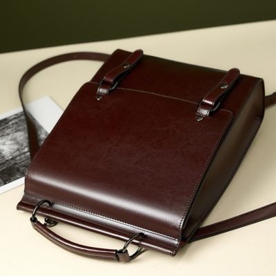 Stylish brown leather tote bag with secure straps, perfect for professional and casual use, offering durability and timeless design.