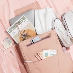 Fashionable pink tote bag with reading glasses, magazine, white sneakers, phone, and stationery essentials for daily use.