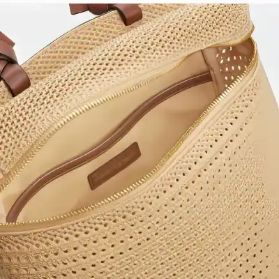 Stylish straw tote bag featuring intricate perforated design, gold trim, and sturdy brown handles, perfect for summer fashion and beach outings.