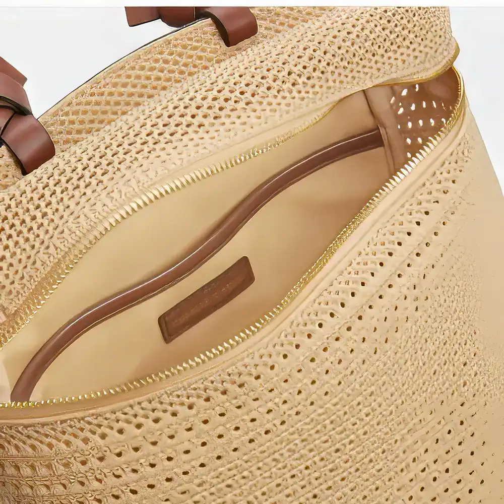 Stylish straw tote bag featuring intricate perforated design, gold trim, and sturdy brown handles, perfect for summer fashion and beach outings.