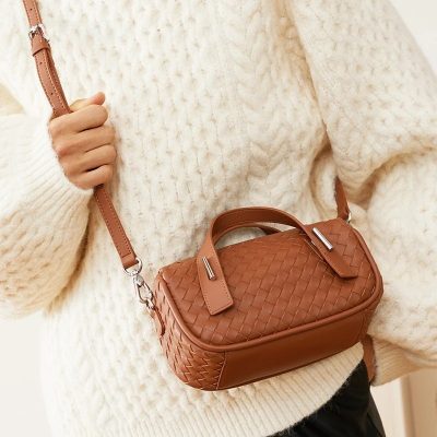 A stylish woven brown handbag with a top handle and adjustable strap, perfect for everyday fashion and enhancing your look.