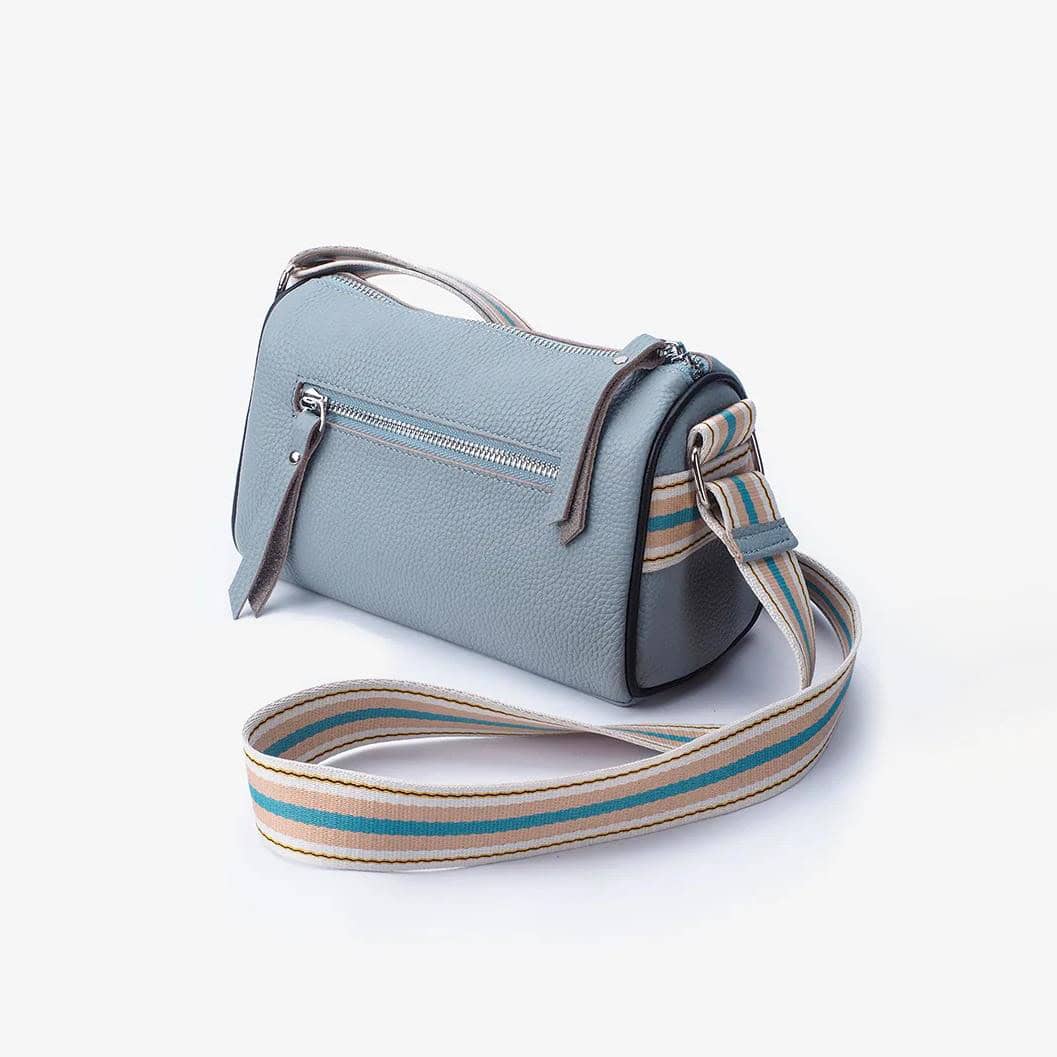 Stylish light blue handbag with silver zipper, adjustable striped strap, and premium textured material, ideal for fashion-forward women seeking luxury accessories.